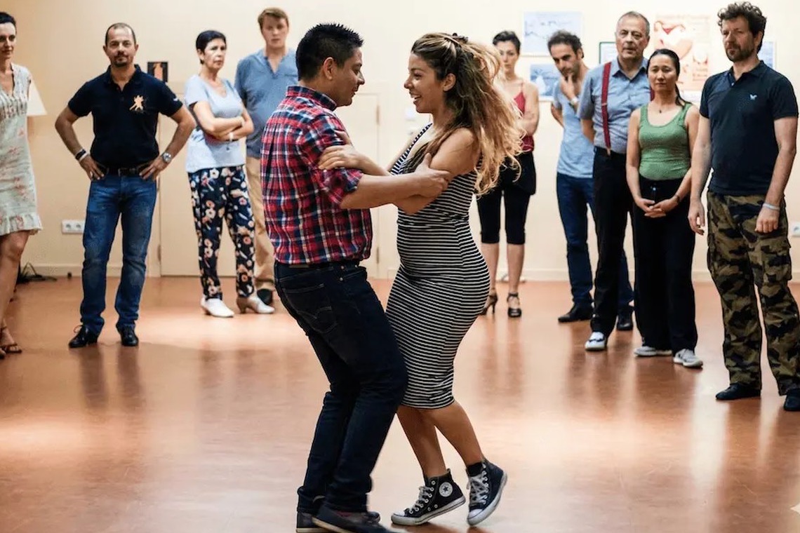 Un cours de tango chez BE-TANGO à Bruxelles : un couple danse pendant que le groupe regarde.