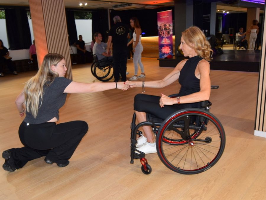 Deux femmes dansent ensemble lors de la journée portes ouvertes du Studio 28, l’une d’elles en fauteuil roulant.